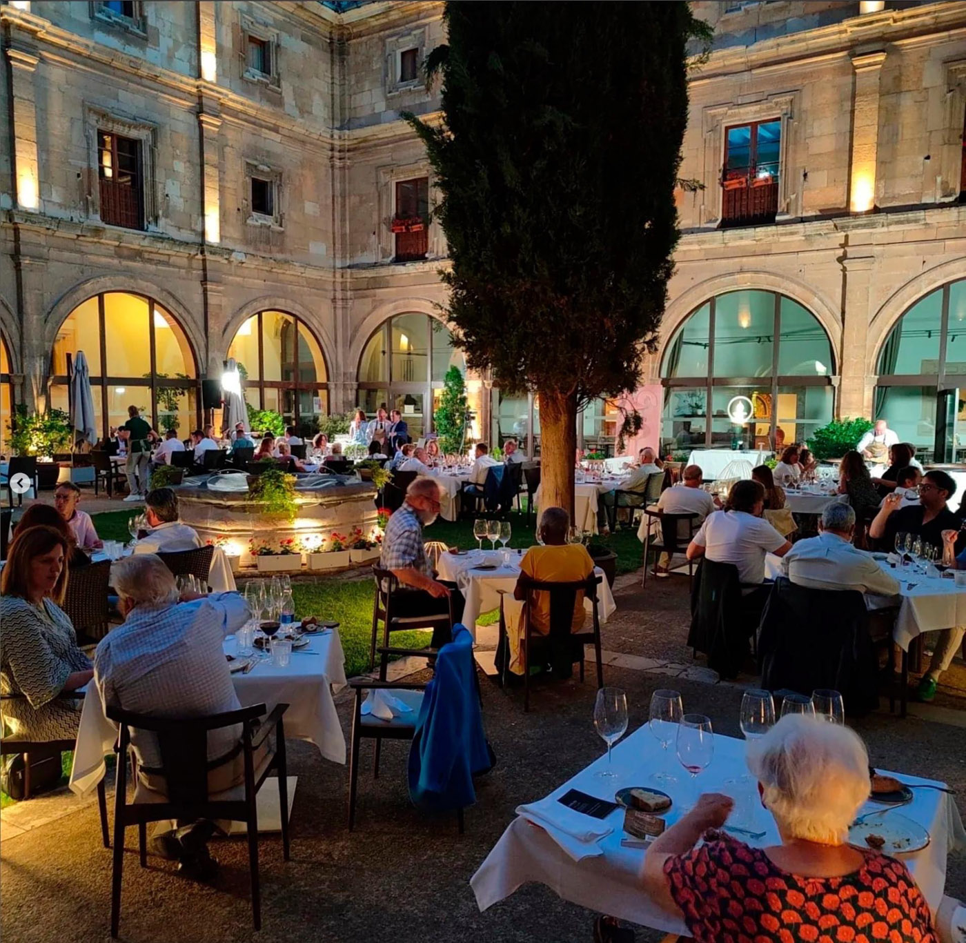imagen con gente sentada a cenar en un claustro de noche