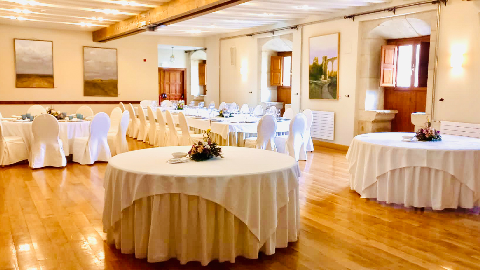 imagen salón san isidoro con varias mesas montadas, tres redondas y una grande rectangular